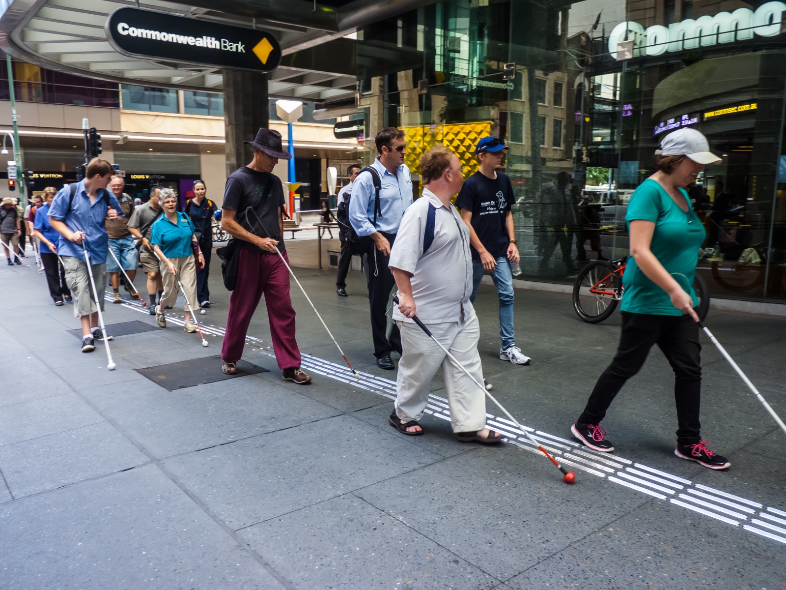 White cane users walking through a city street on International White Cane Day.